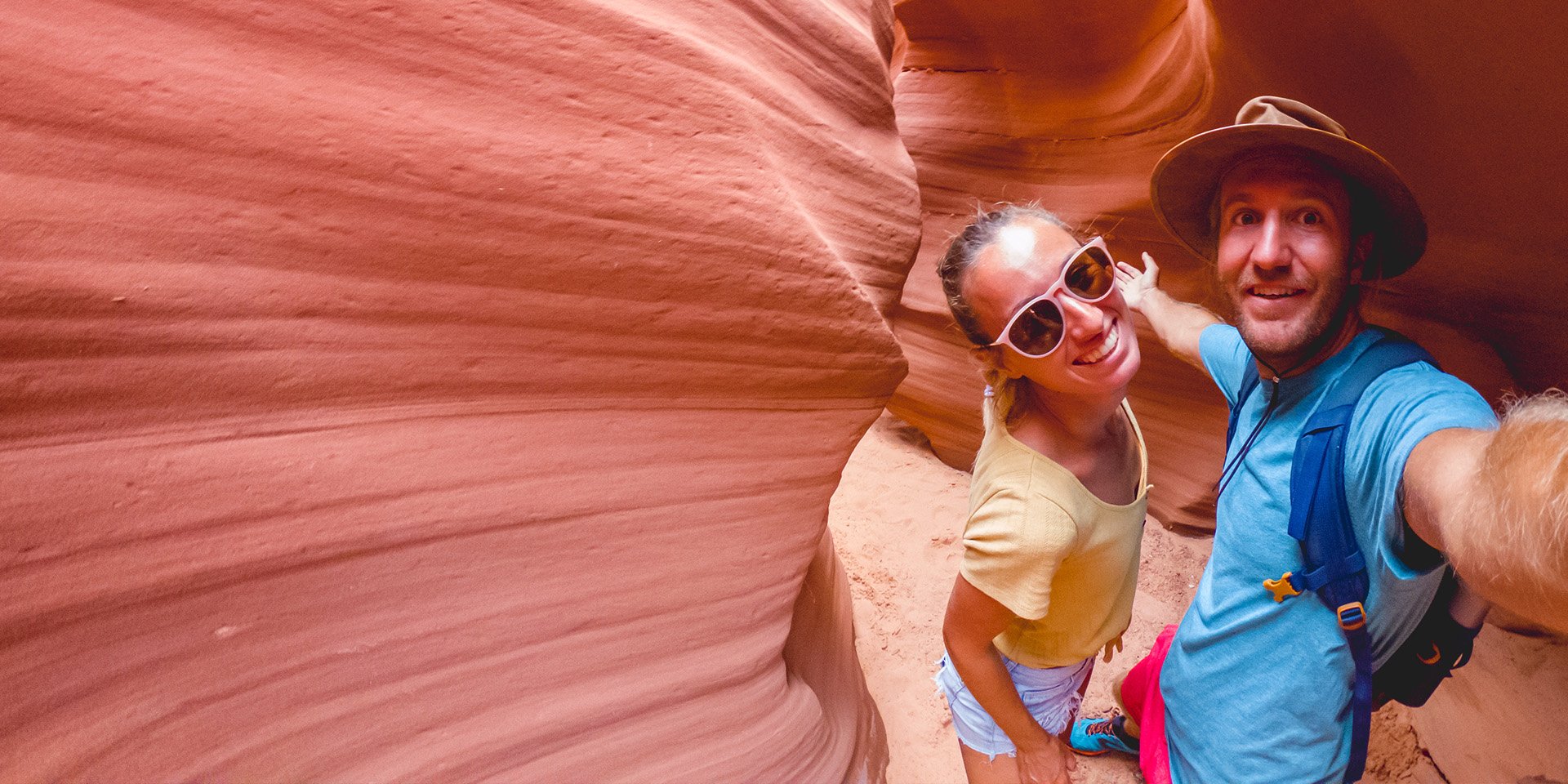 Two happy hikers taking a selfie at the bottom of a canyon.