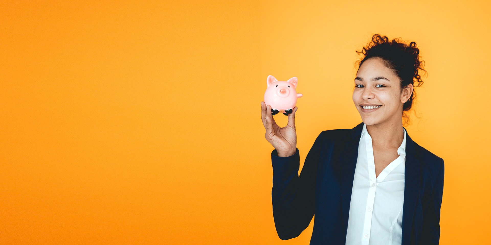 A happy businesswoman holding a small piggy bank in her right hand. 