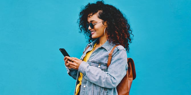 A joyful customer effortlessly manages her finances using Desert Financial overdraft services, smiling while checking her phone for account updates.