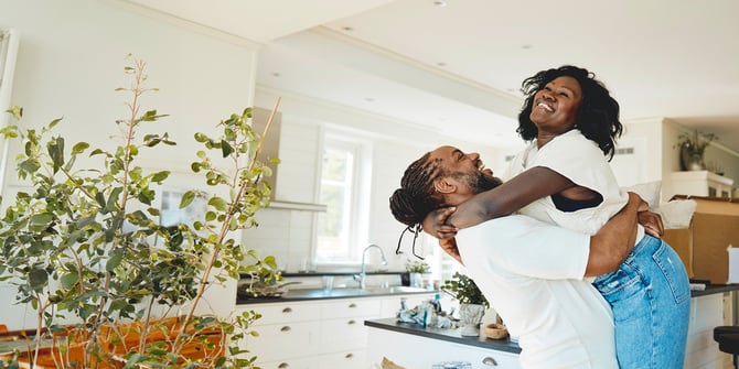 New homeowners celebrate in their kitchen, surrounded by unpacked boxes. Husband joyfully lifts his wife in a warm embrace, marking a moment of happiness in their first home together. New homeowners celebrate in their kitchen, surrounded by unpacked boxes. Husband joyfully lifts his wife in a warm embrace, marking a moment of happiness in their first home together.
