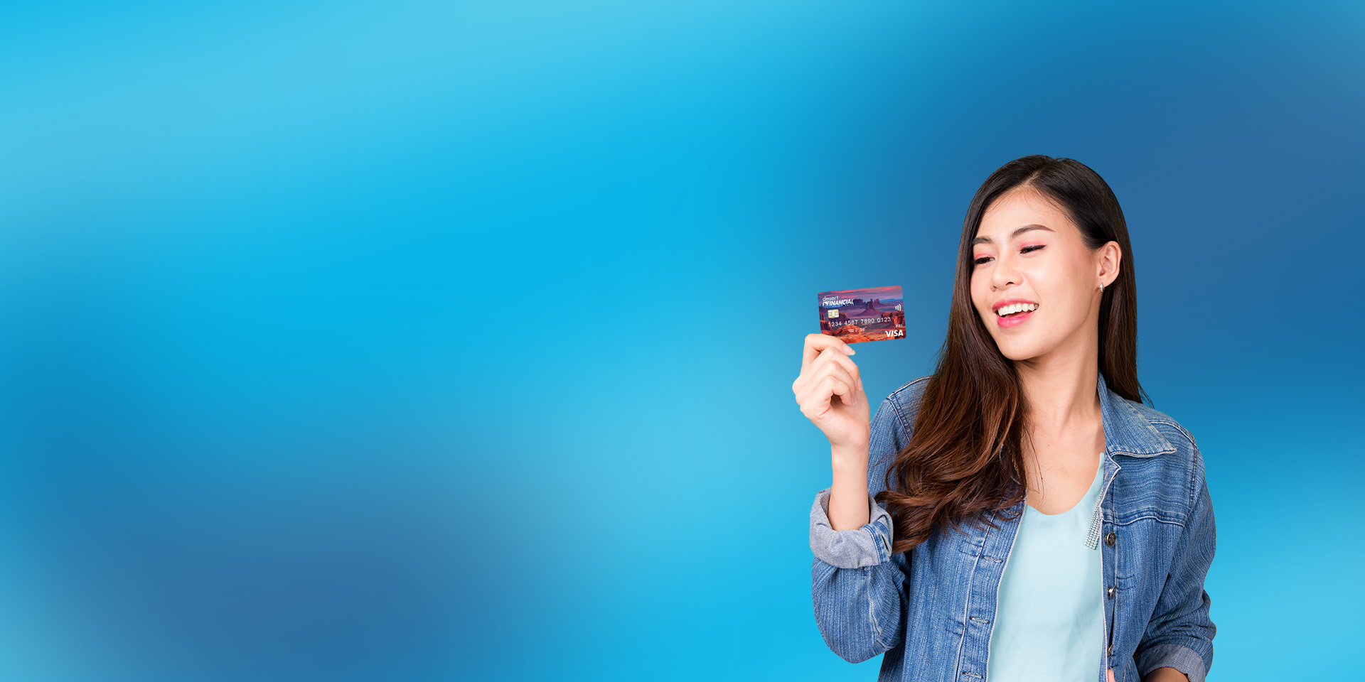 A woman holding a Desert Financial debit card and smiling