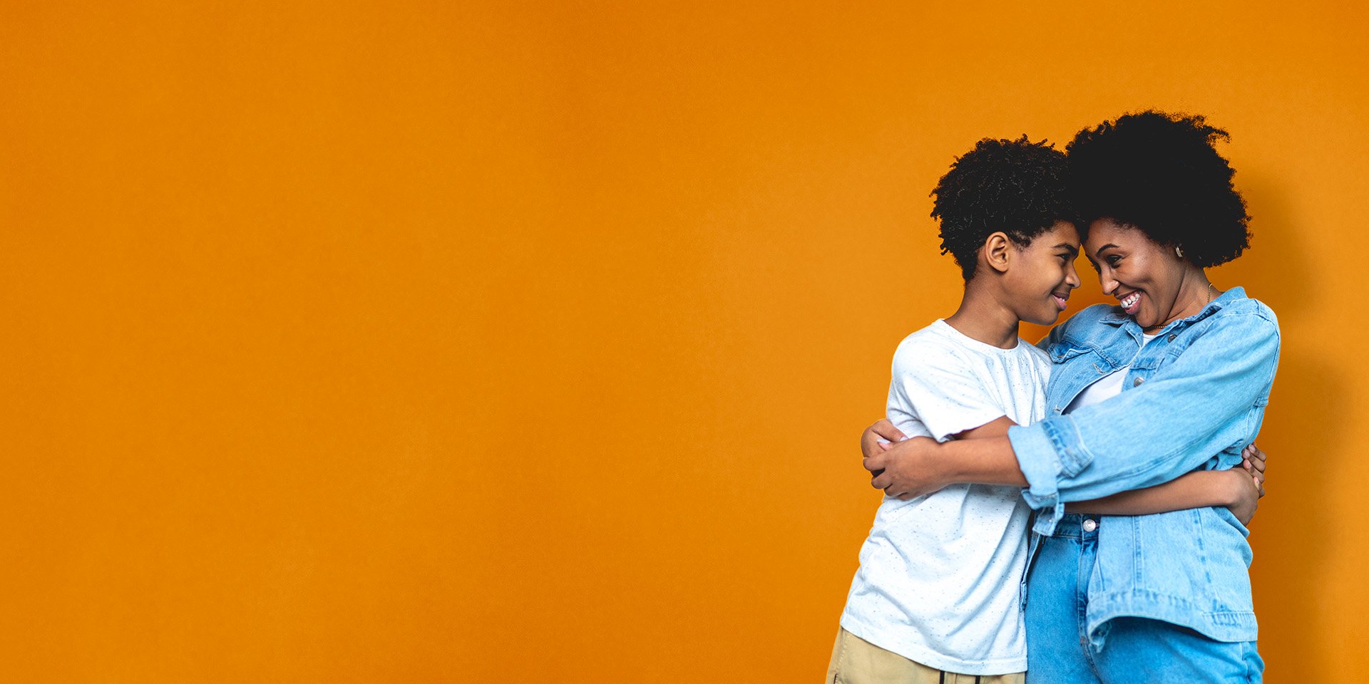 Mother and son share a tender embrace, looking into each other's eyes with their foreheads touching.