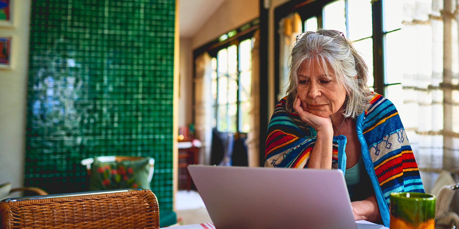 Elderly woman navigates Desert Financial's website, scrolling through the FAQ section on her laptop to find valuable information.