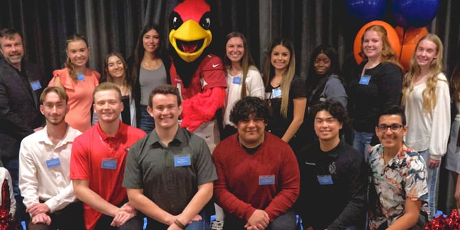 High school student-athletes awarded Desert Financial's scholarship stand with Arizona Cardinals cheerleaders and mascot, Big Red, celebrating their achievements.